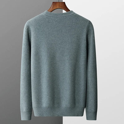 grau-kaschmirpullover-mit-kabelstrickmuster-elegant-gefaltet-auf-einem-grauen-hintergrund-neben-einer-schwarzen-uhr